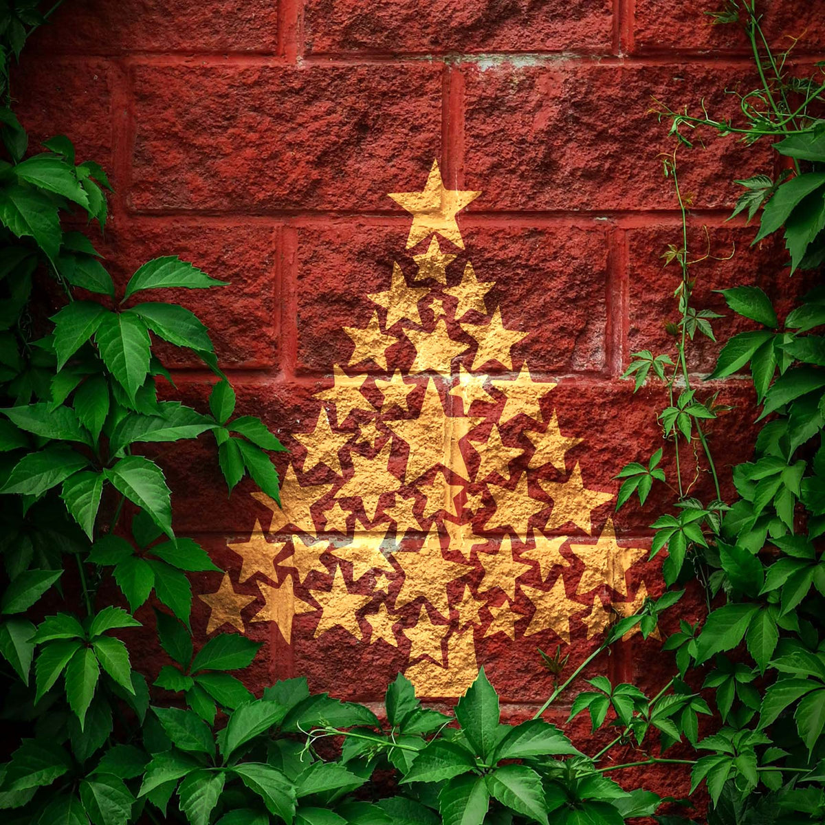 Gold Starry Christmas Tree Stencil displayed on a red brick wall framed by green ivy.