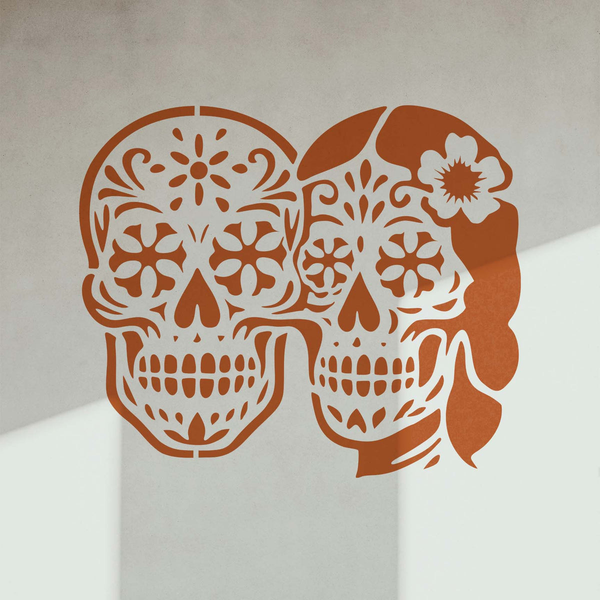 Sugar Skull Couple Stencil displays matching floral skull faces on a softly shadowed interior wall