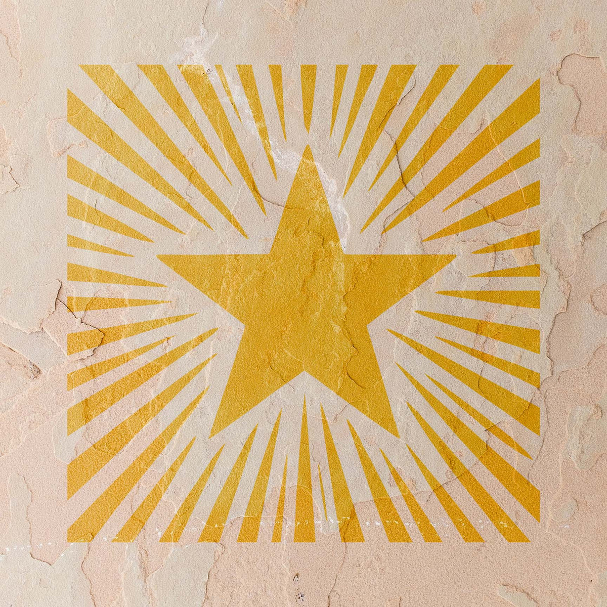 Against a weathered stucco wall, the Sunburst Star Stencil appears in warm golden yellow