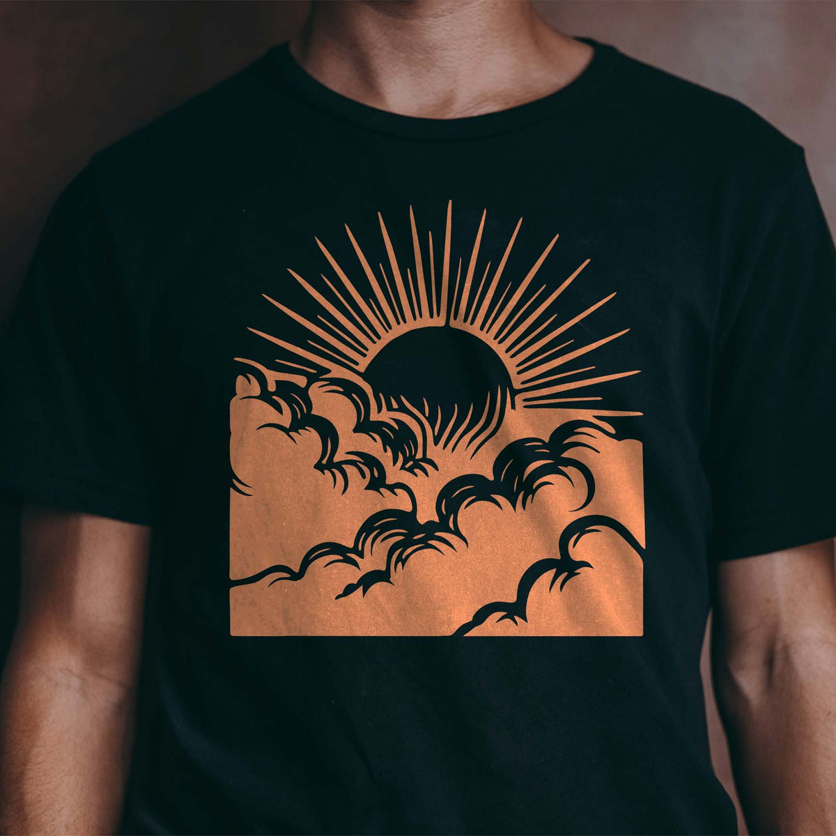 Sunrise Above Clouds Stencil printed in warm orange across a black T-shirt