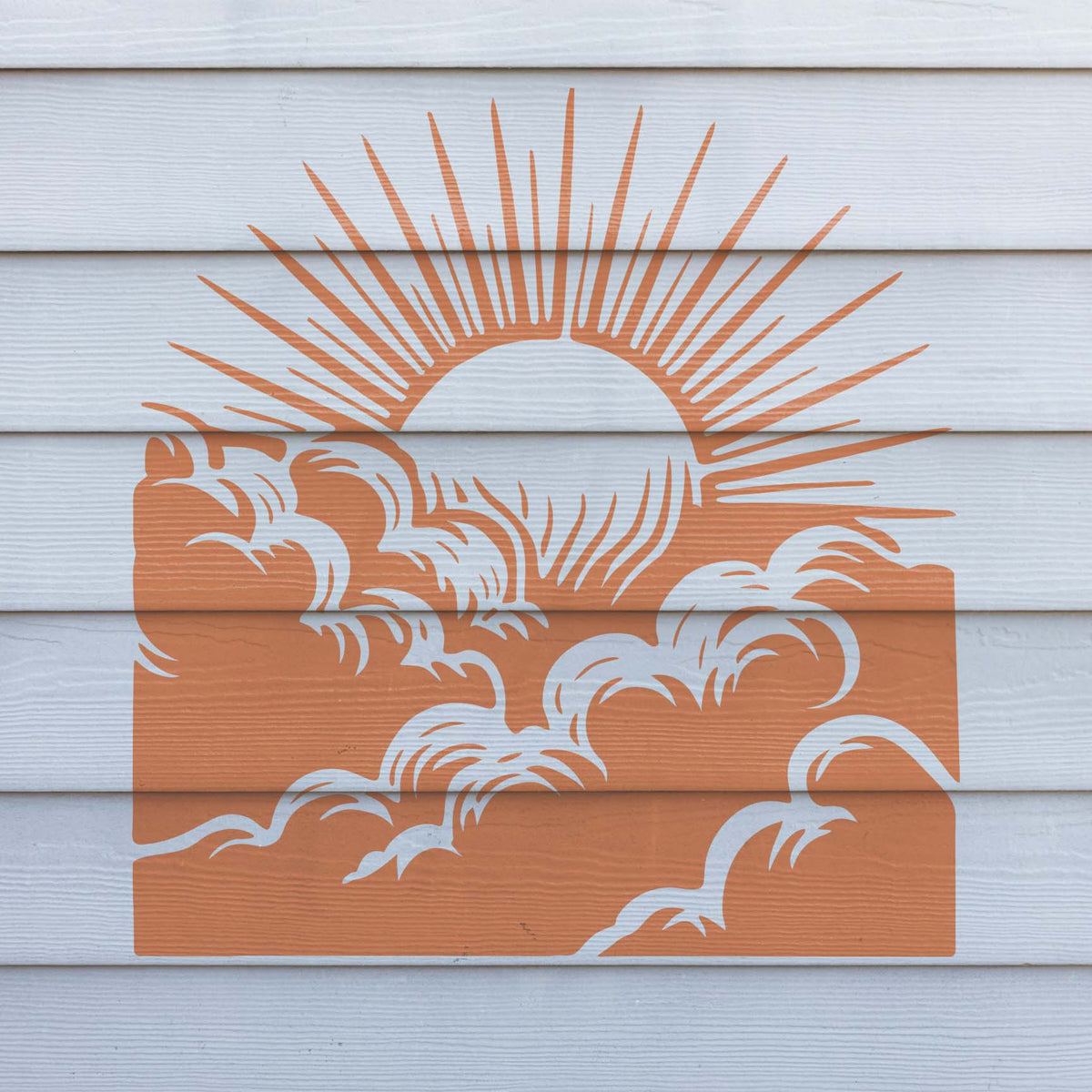Sunrise Above Clouds Stencil displayed in orange over white exterior wall siding