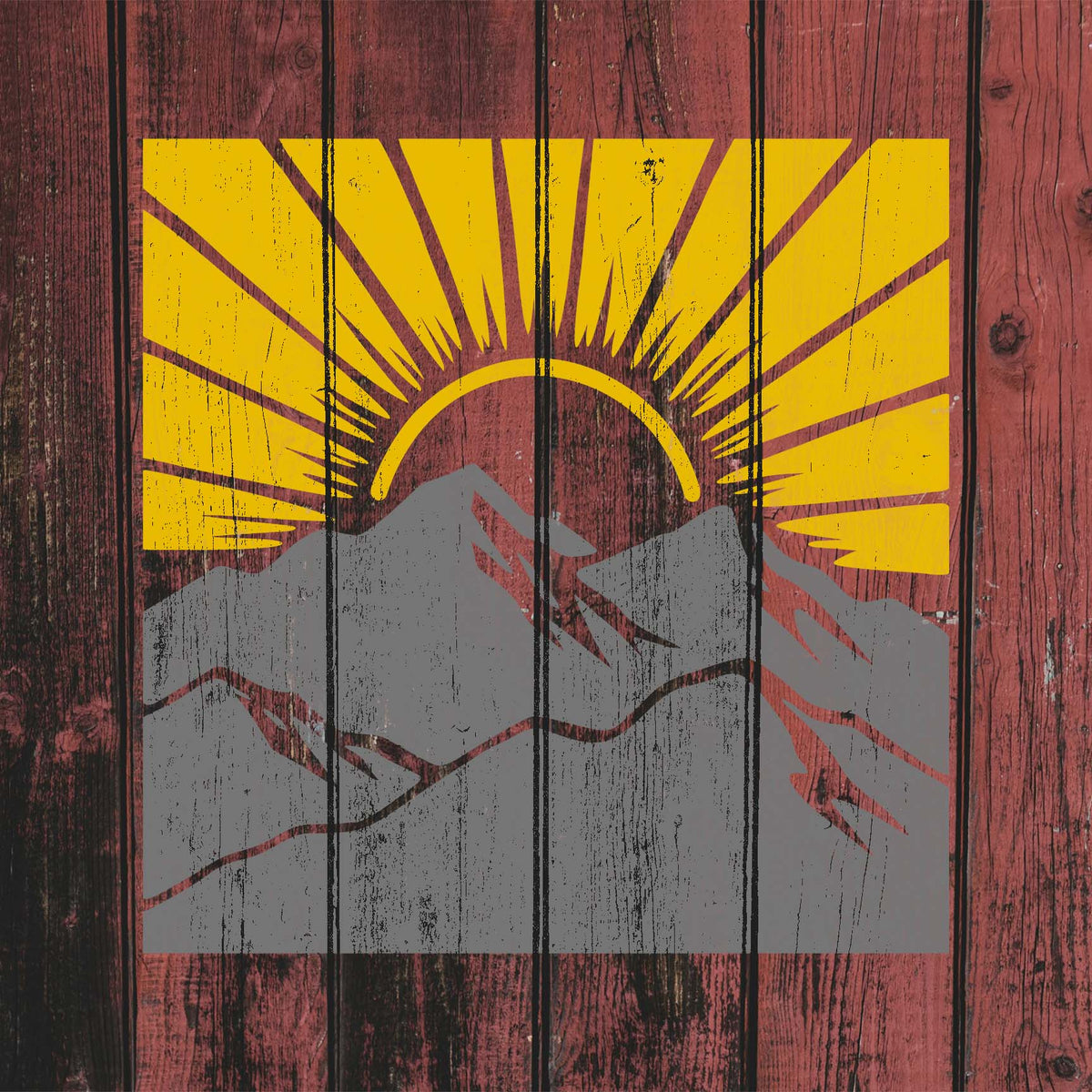 Rustic red wood displays Sunrise Mountain Landscape Stencil with gray peaks and vivid yellow rays