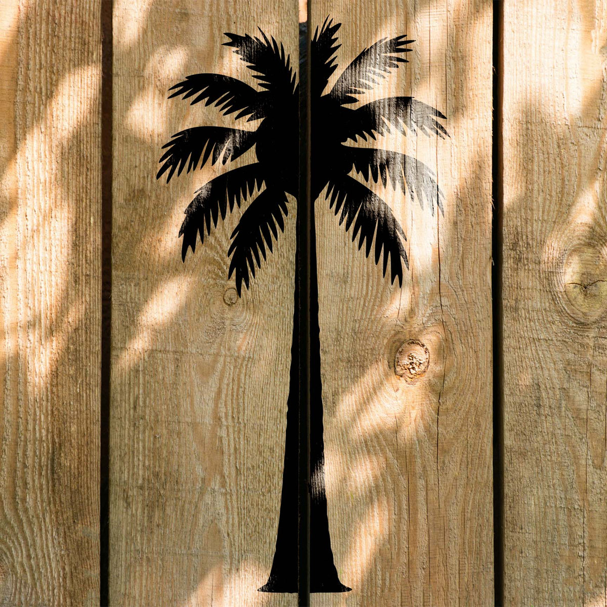 Striking black palm tree stencil stretching across sunlit rustic wood planks