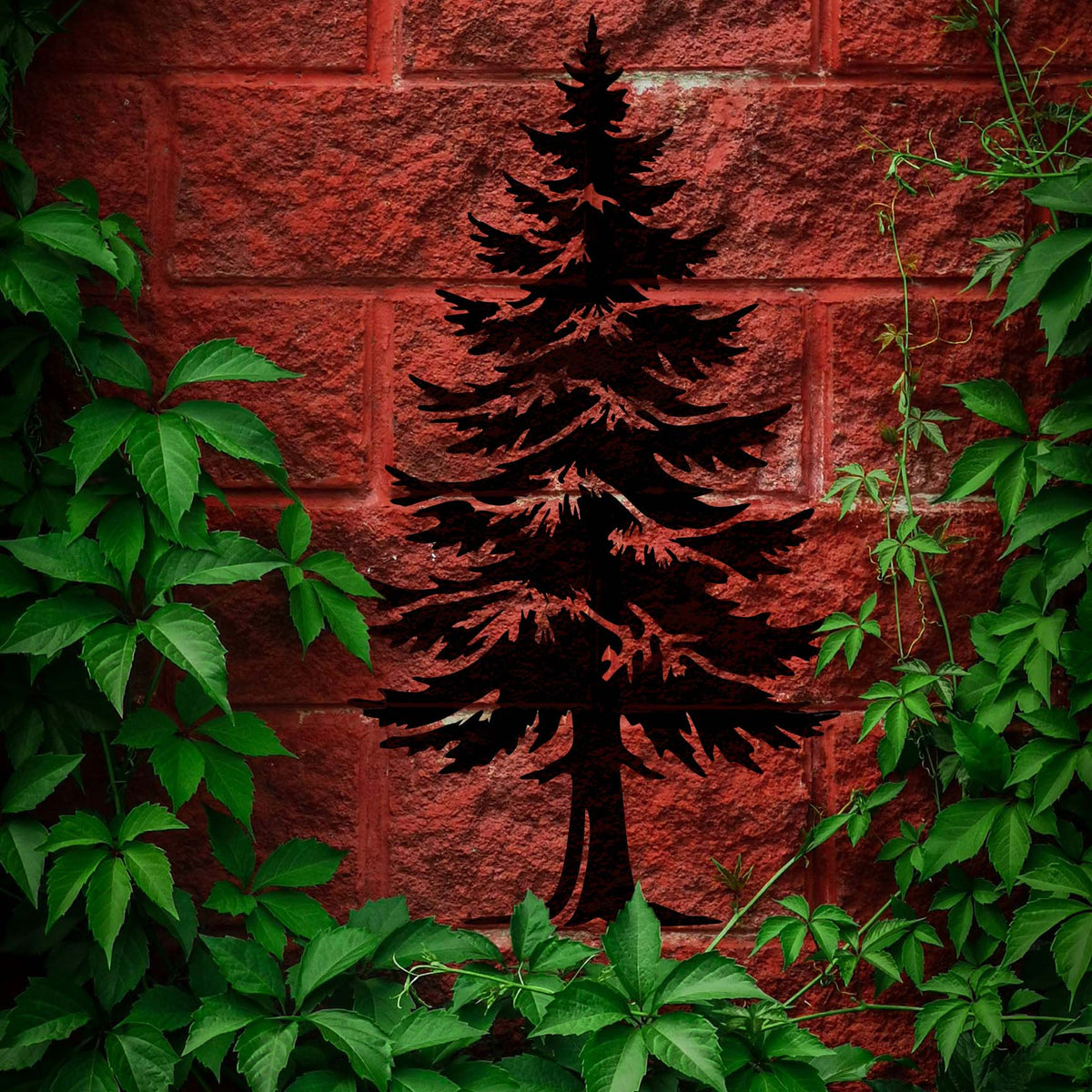 Dramatic black pine tree stencil framed by leafy vines on red brick
