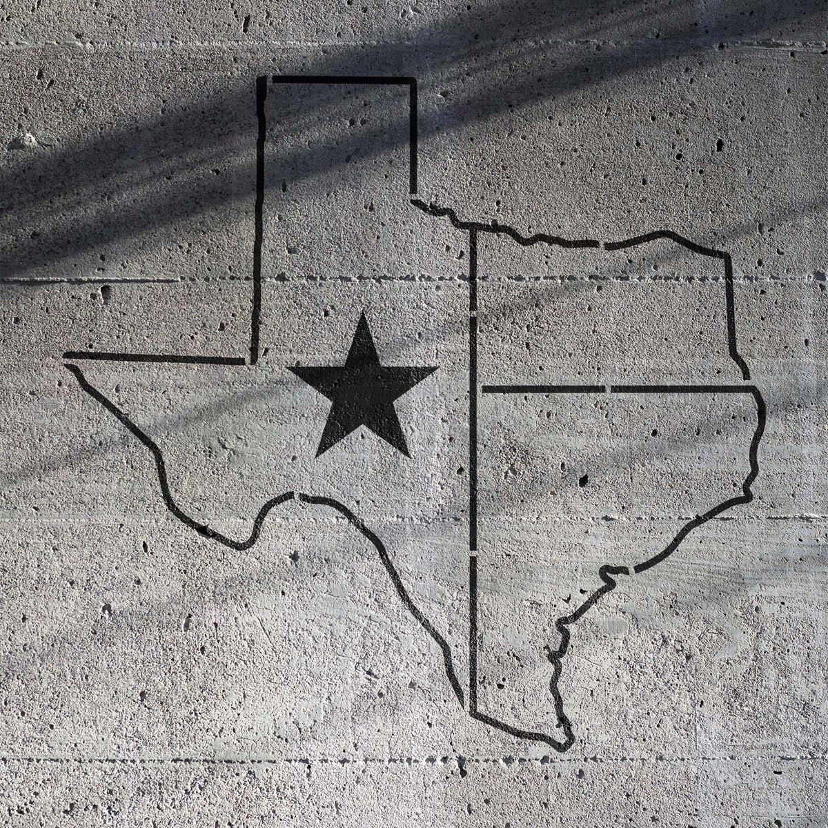 Black Texas Lone Star State Outline Stencil stands out across a rough gray concrete wall