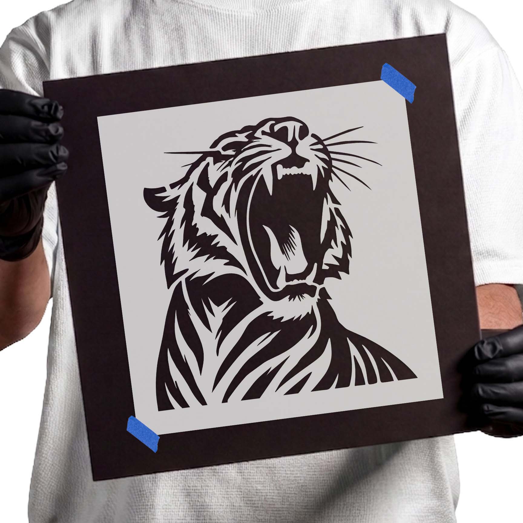 Person holding Fierce Roaring Tiger Stencil taped to black cardboard