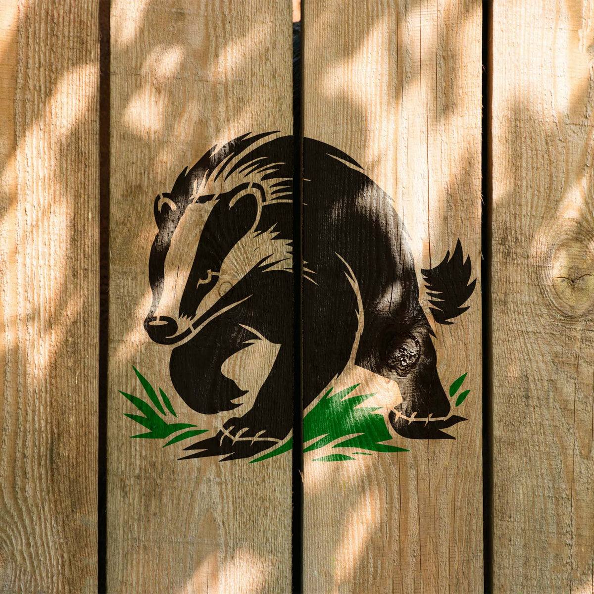 Walking badger stencil painted in black and green on wooden fence