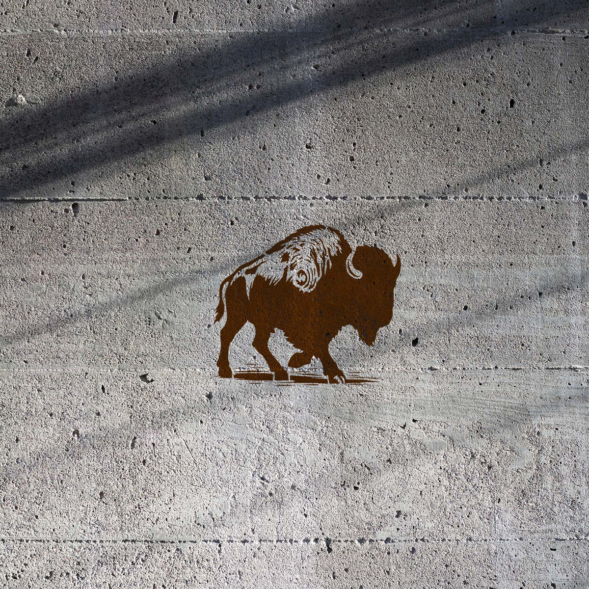 Walking Bison Side Profile Stencil painted brown on a textured concrete wall with lowered head.