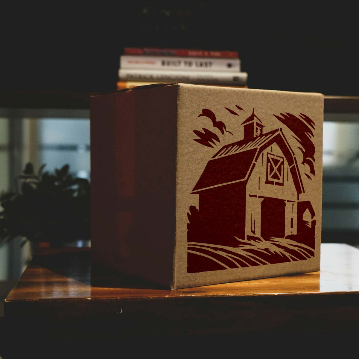 Weathered Farm Barn Stencil printed in dark red on a kraft storage box on a wooden table.
