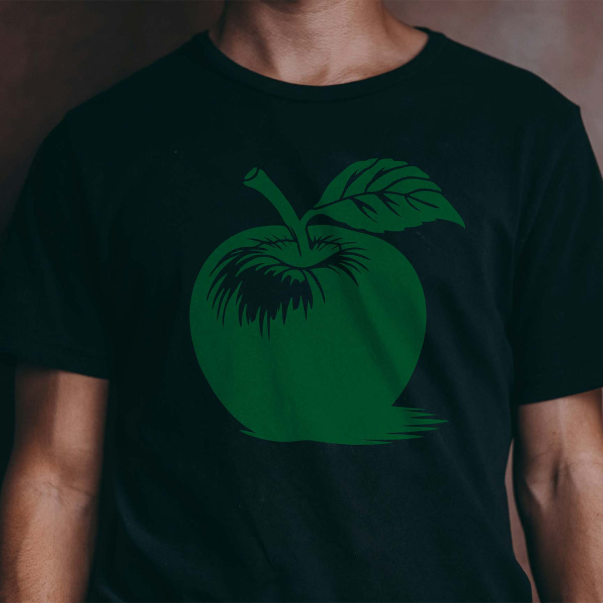 A black T-shirt features the Whole Apple with Stem and Leaf Stencil in rich green across the chest.