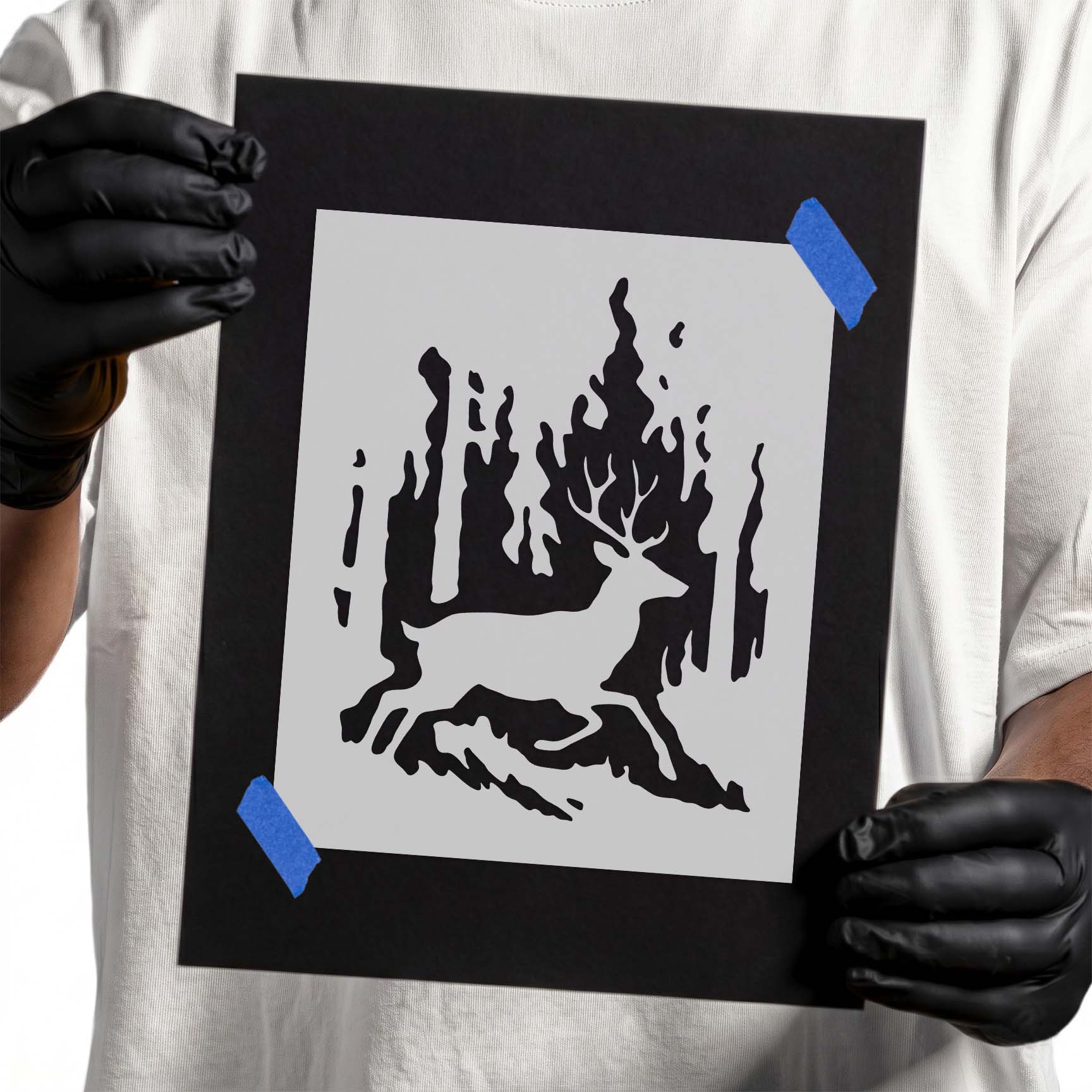 Gloved hands holding Wildfire Buck stencil taped to black cardboard