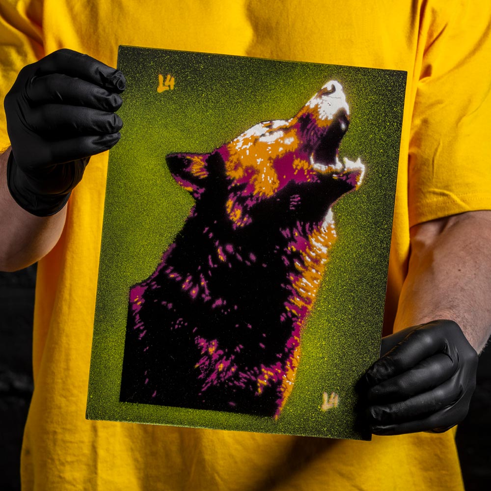 Howling wolf layered stencil artwork in purple, orange, and green spray paint held by artist wearing black gloves