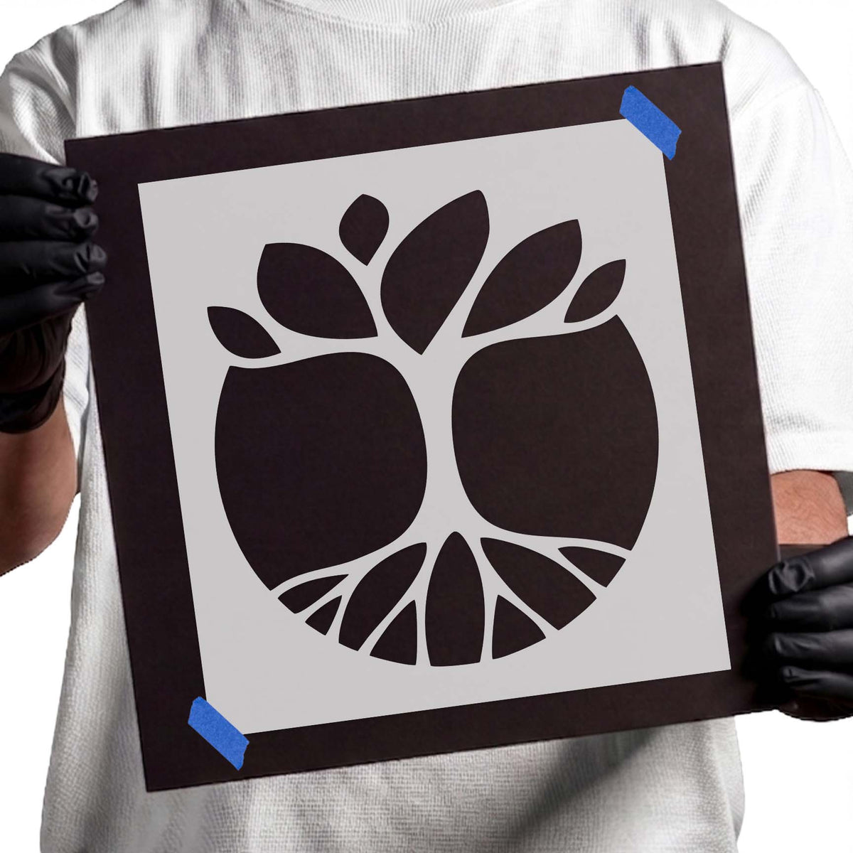 Circular tree stencil with spreading roots, branching limbs, and bold leaves