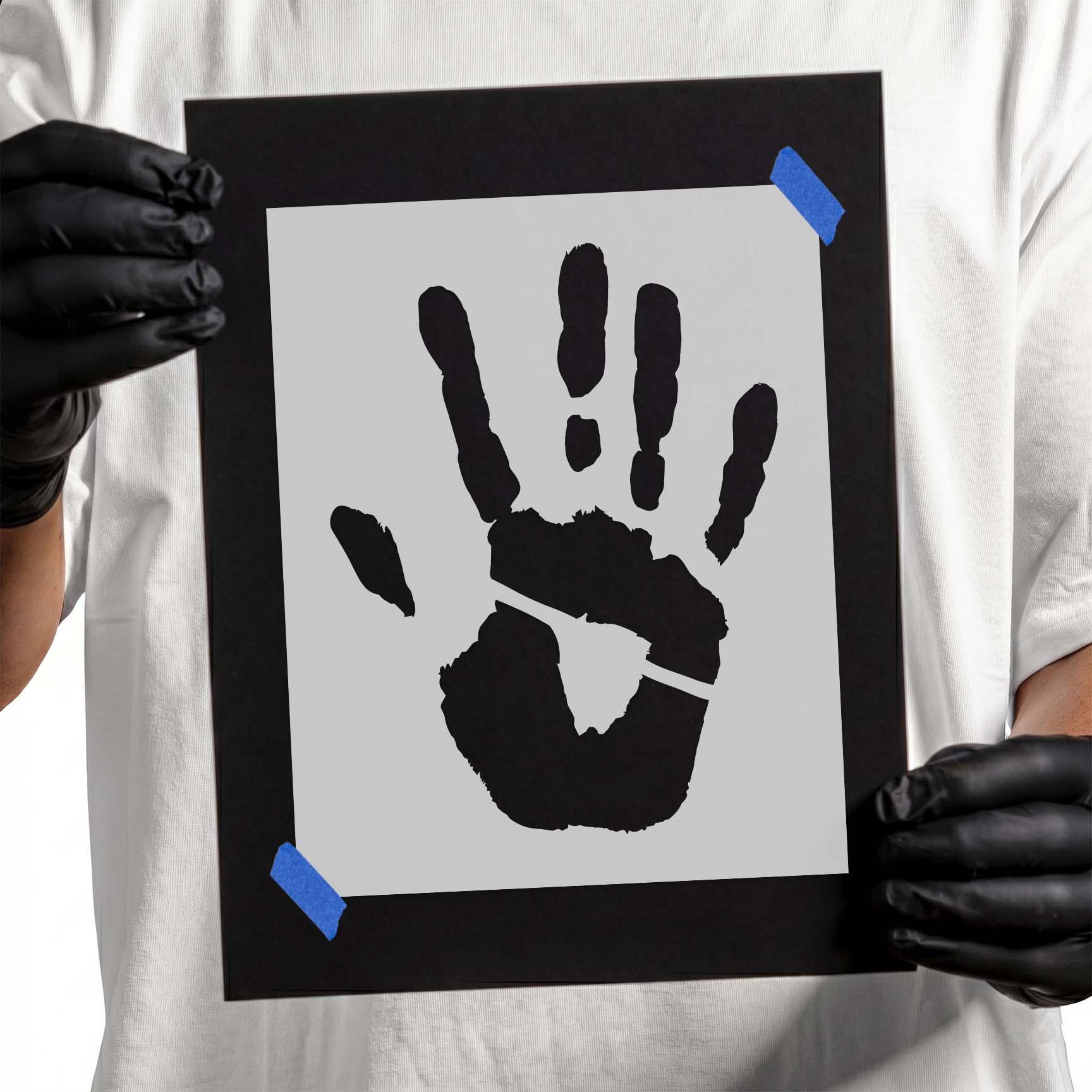 Person holding a laser-cut Handprint Stencil taped to cardboard