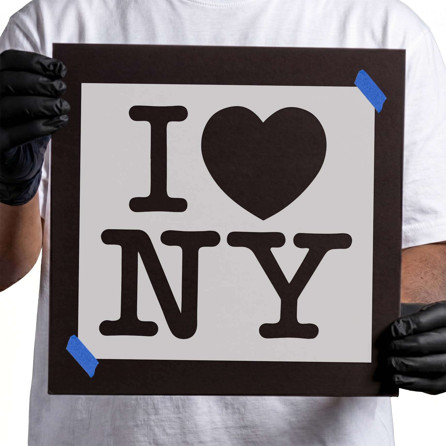 Gloved hands holding Mylar I Love New York Stencil taped to cardboard