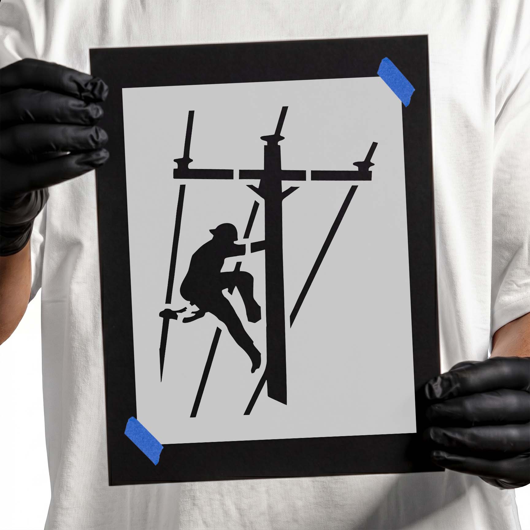 Person holding laser-cut Lineman Mylar Stencil taped to cardboard