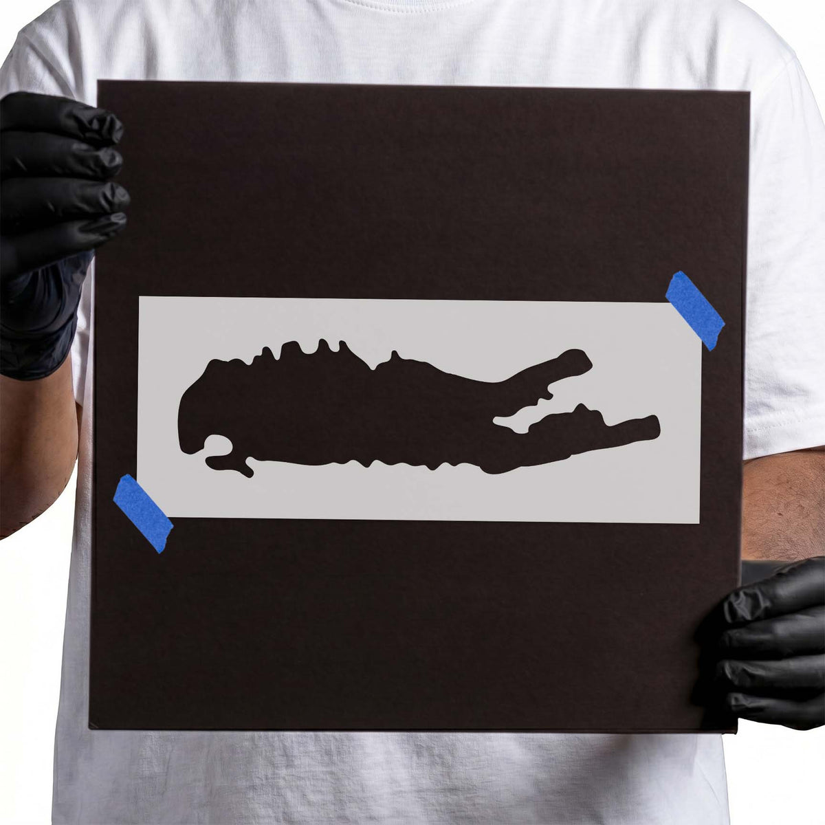 Person holding laser-cut Long Island Shape Stencil taped to cardboard
