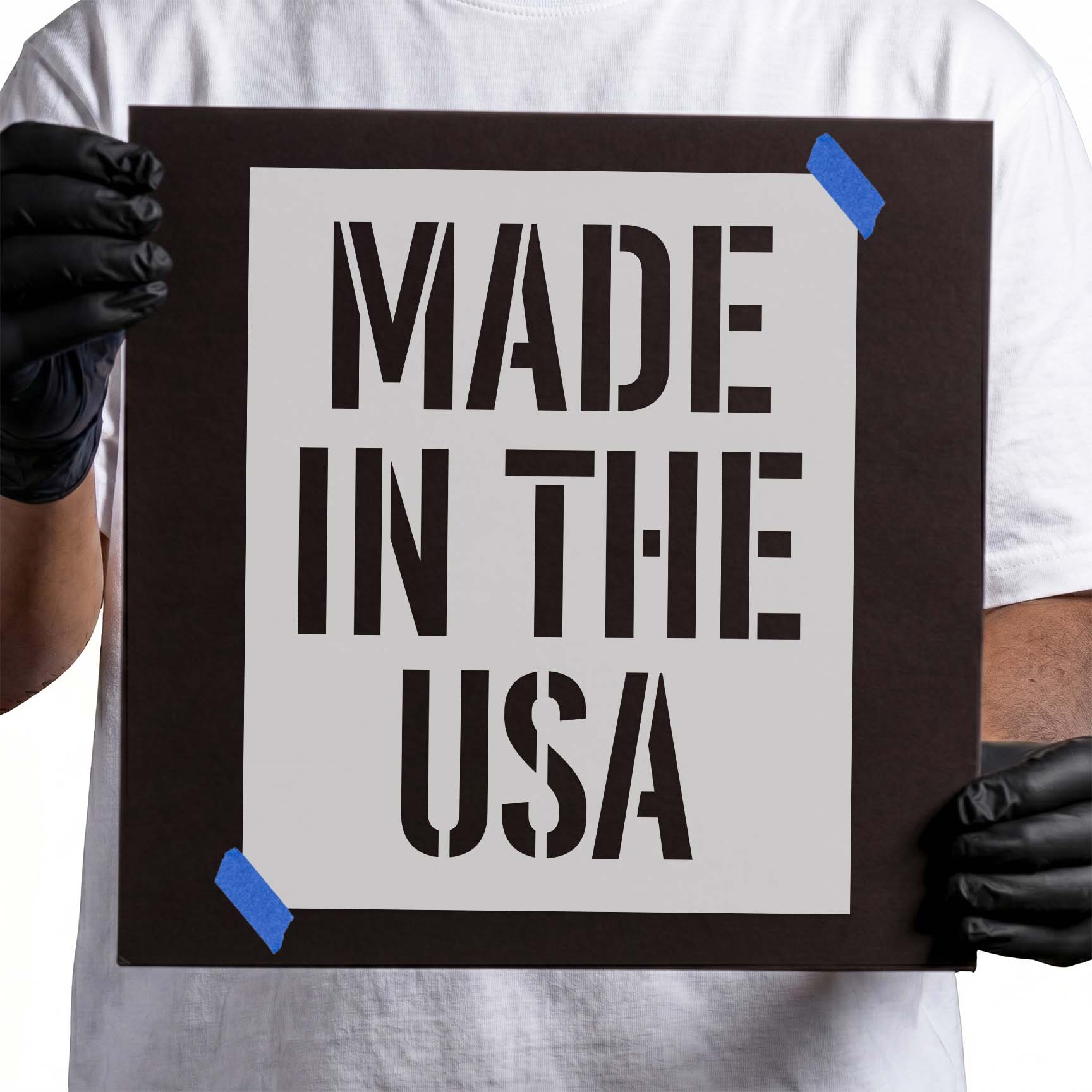Gloved hands holding laser-cut Made in Usa Stencil taped to cardboard
