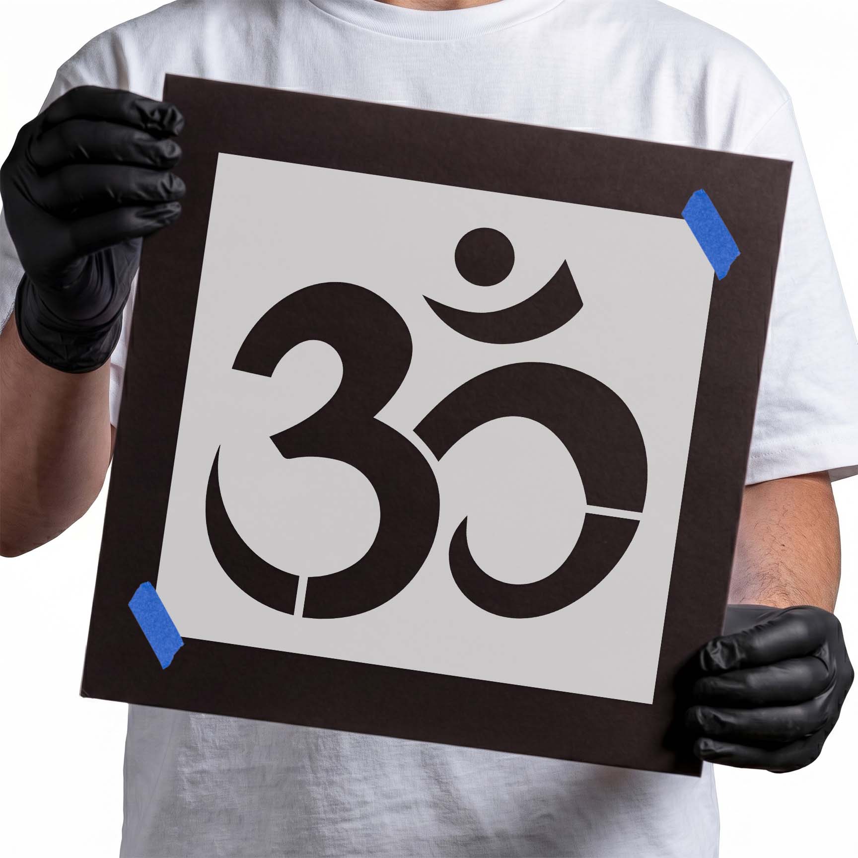 Person holding reusable Om Symbol Stencil taped on cardboard
