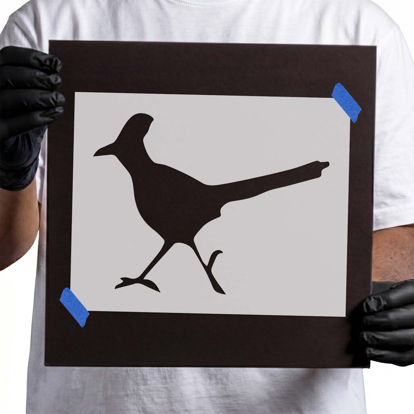 Person holding a Mylar Roadrunner Stencil taped on cardboard