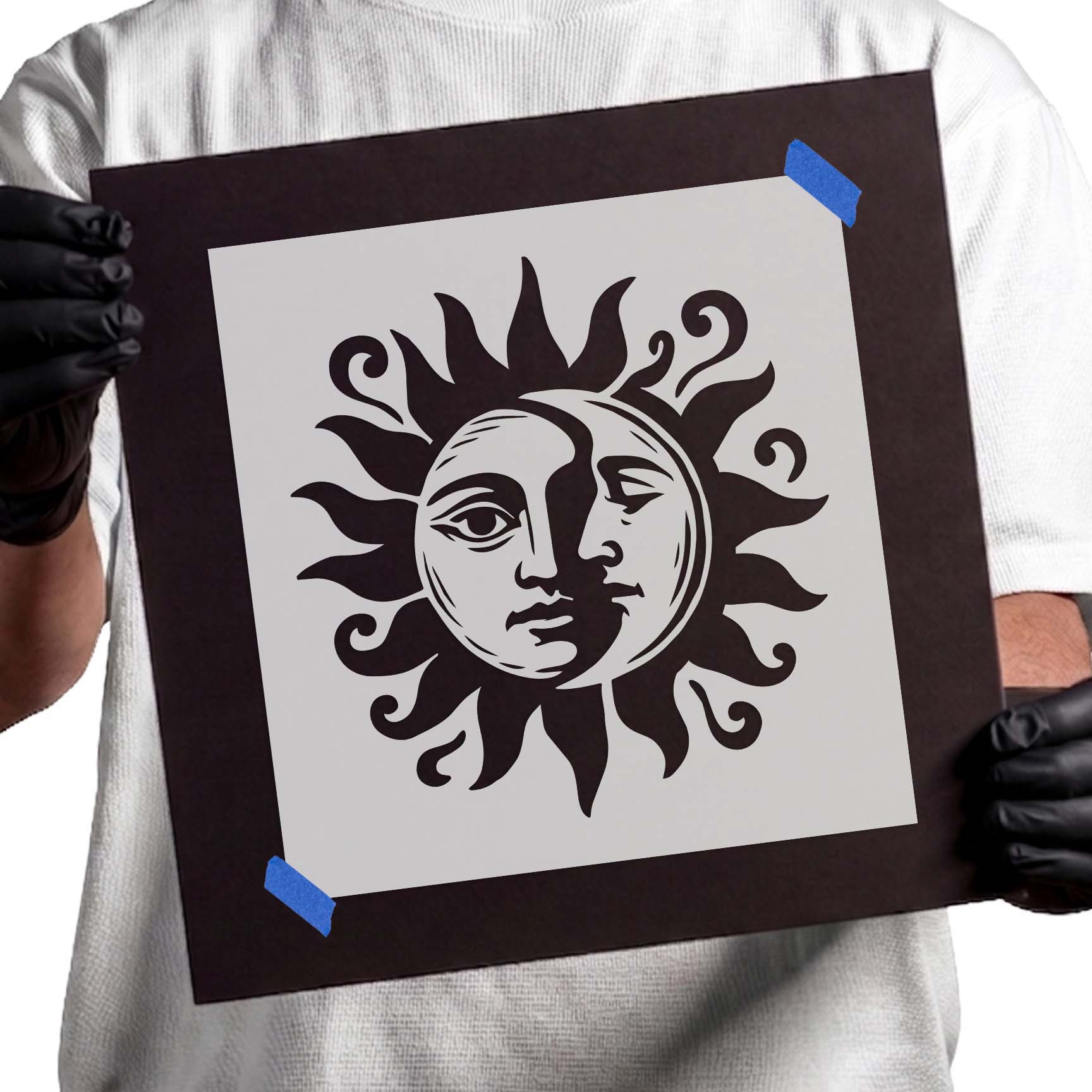 Person holding Celestial Sun and Moon Face Stencil taped to cardboard