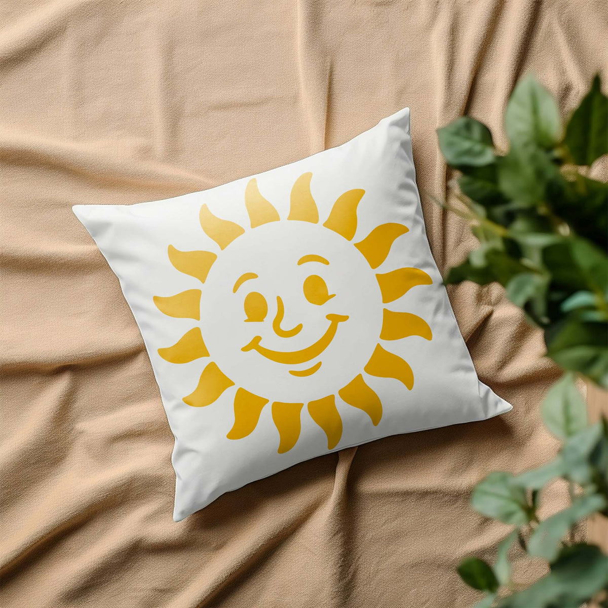 A cheerful yellow Cheerful Smiling Sun Face Stencil brightens a white pillow on soft beige fabric.