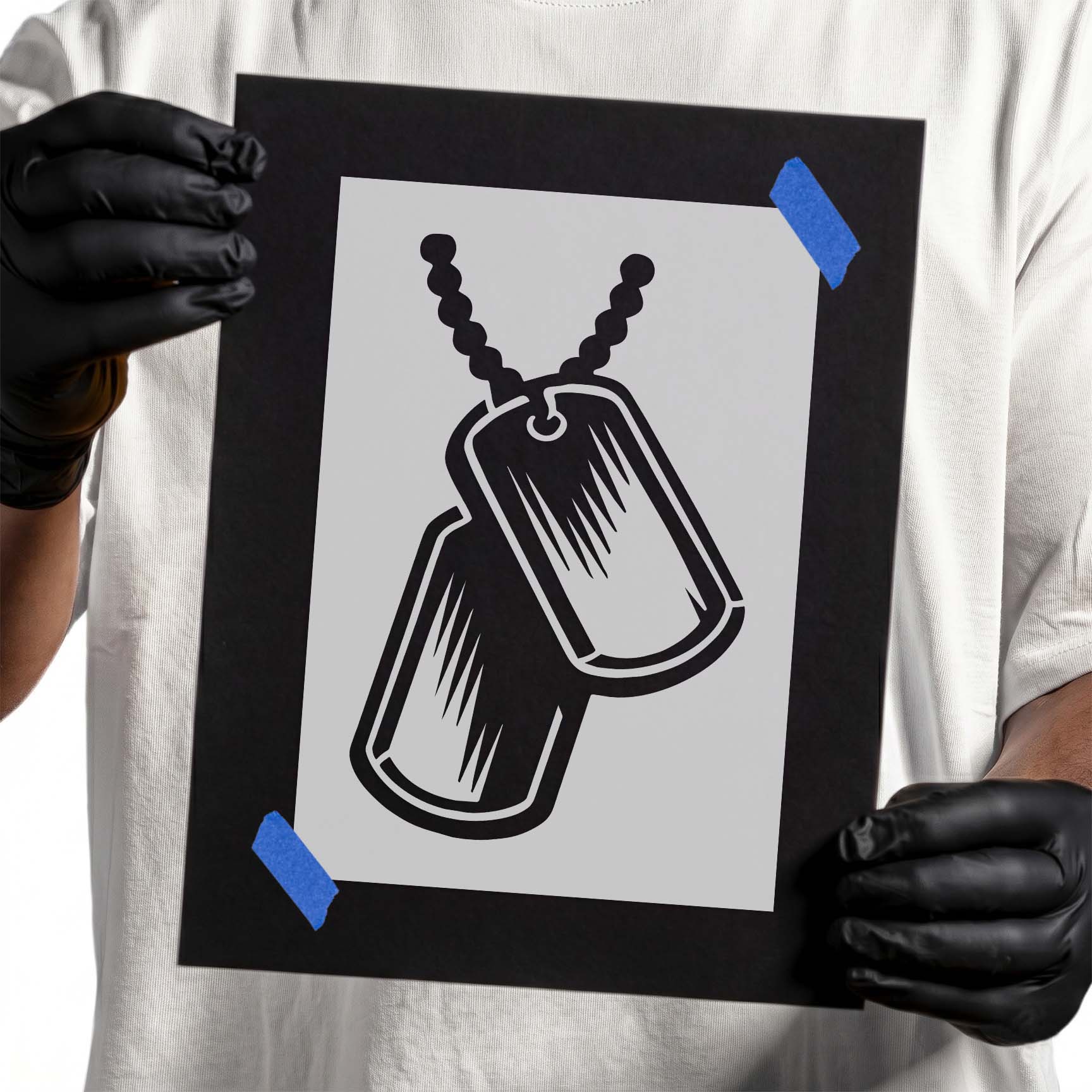 Person holding Classic Dog Tags Stencil taped to cardboard