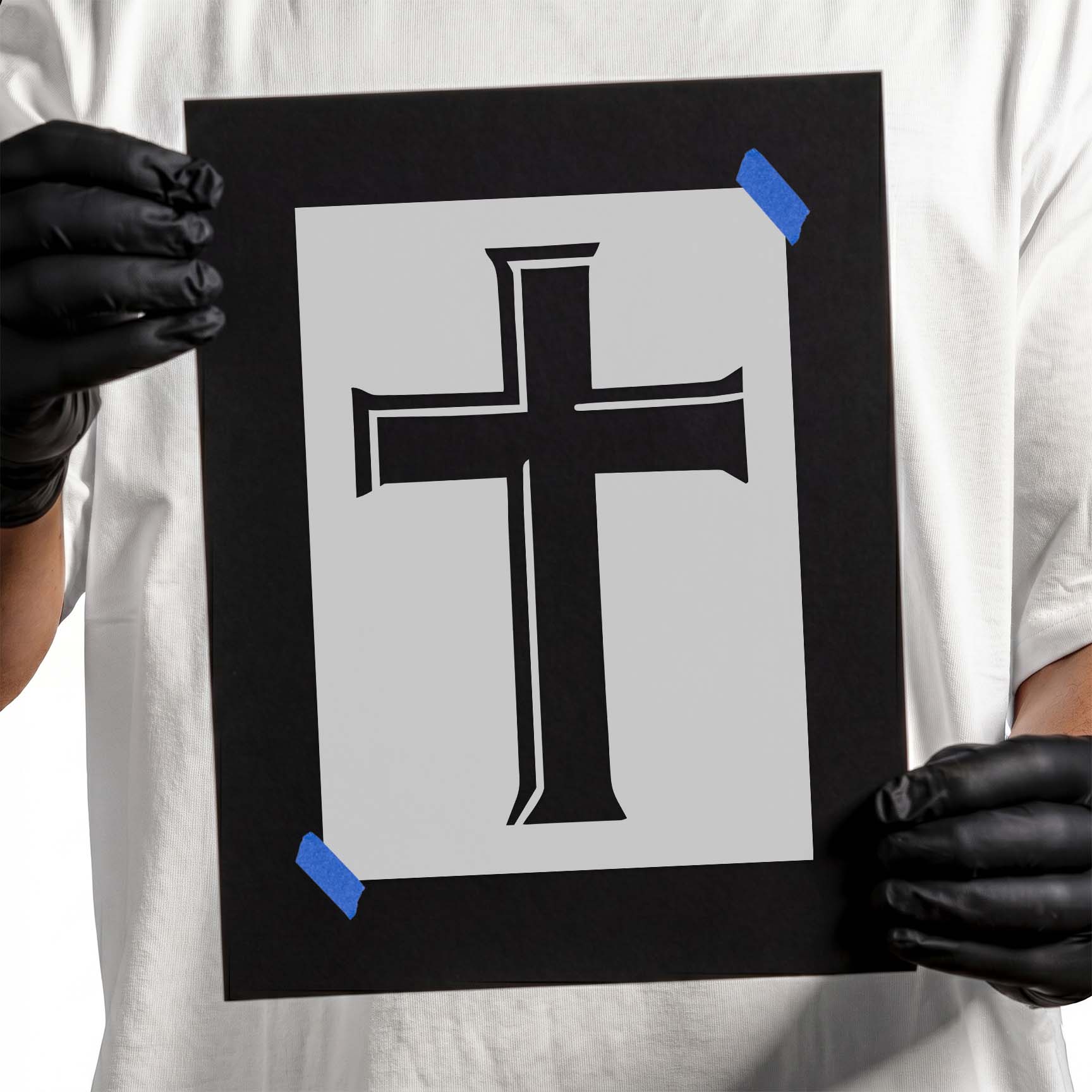 Person holding Classic Latin Cross Stencil taped to black cardboard