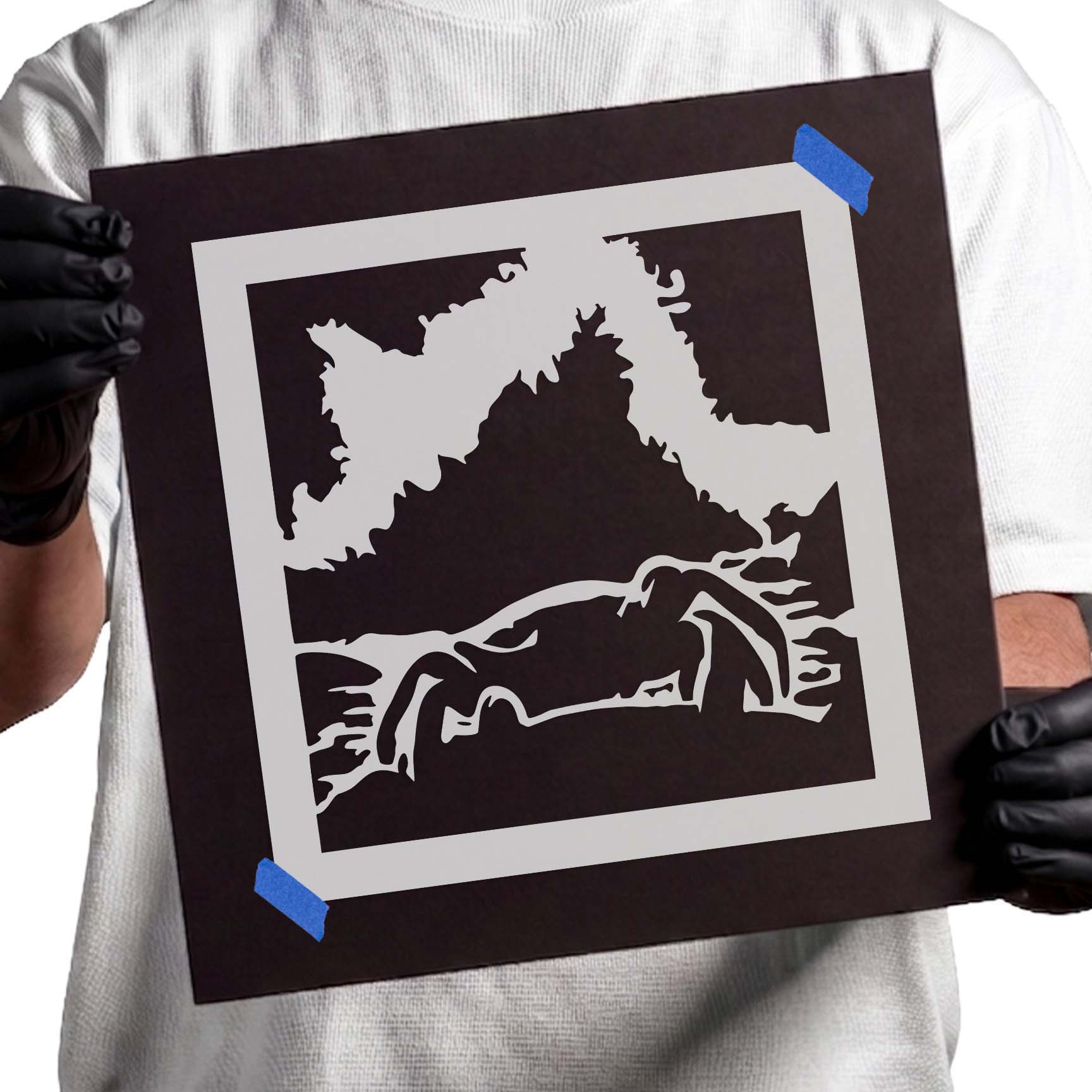 Person holding Coastal Crab Scene Stencil taped to black cardboard