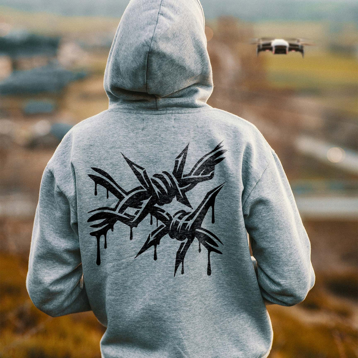 A gray hoodie features the Dripping Barbed Wire Graffiti Stencil with sharp black spikes and paint drips.