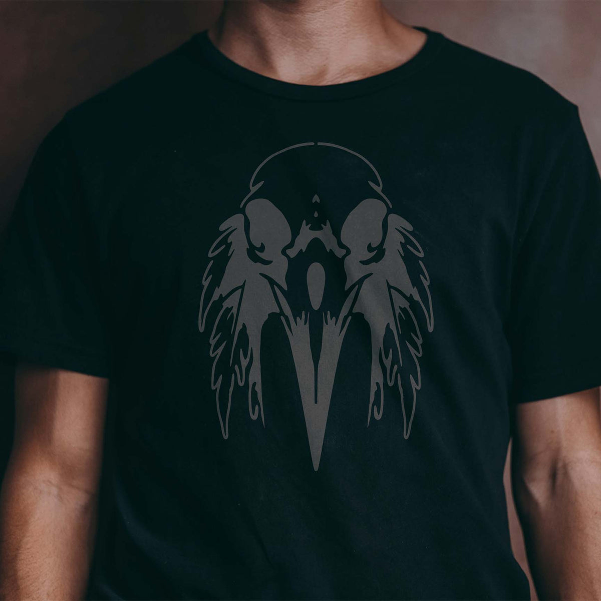 Dark raven imagery gives the Feathered Raven Skull Stencil a haunting look across a black shirt
