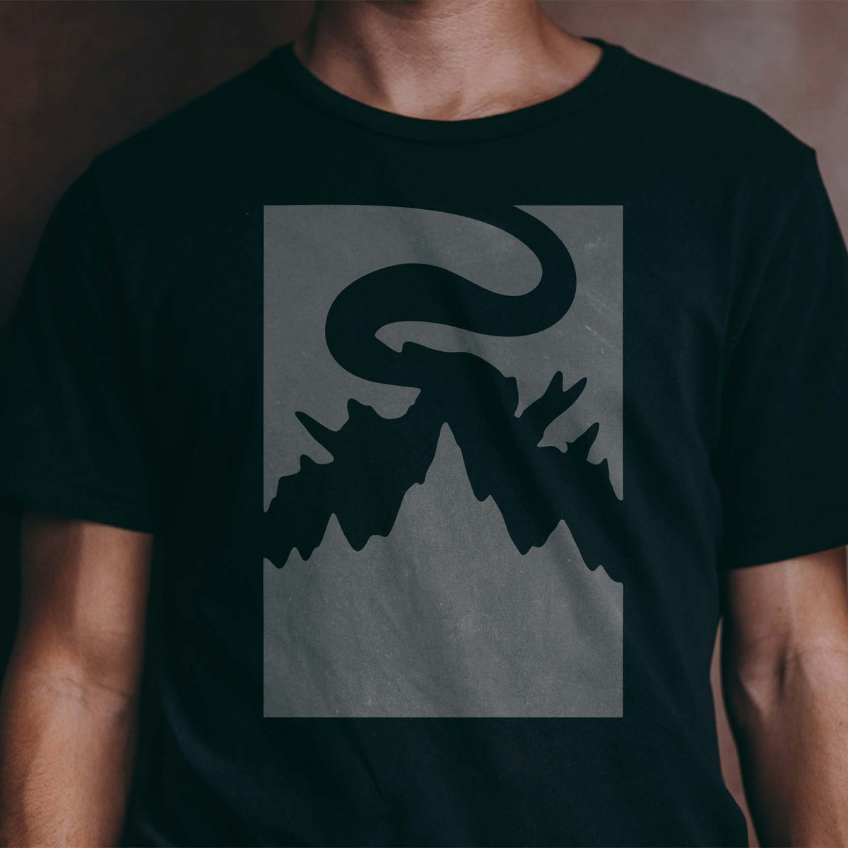 Foggy Mountain Landscape Stencil creates a bold mountain silhouette across a dark black shirt.