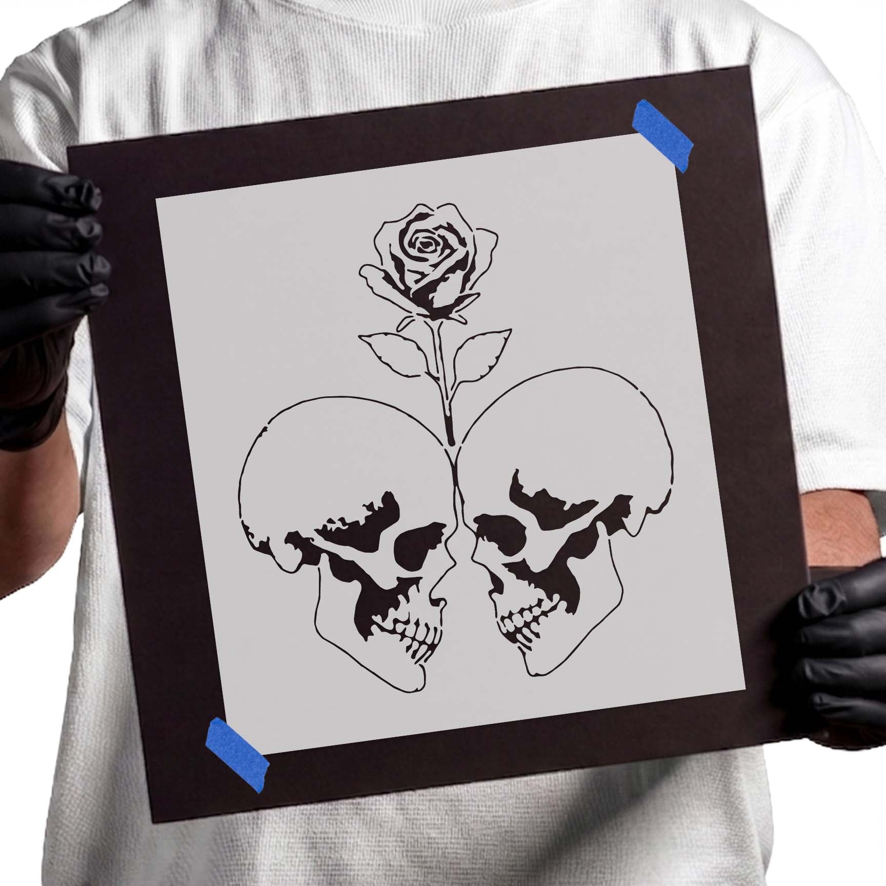 Two facing skulls with a blooming rose stencil design

