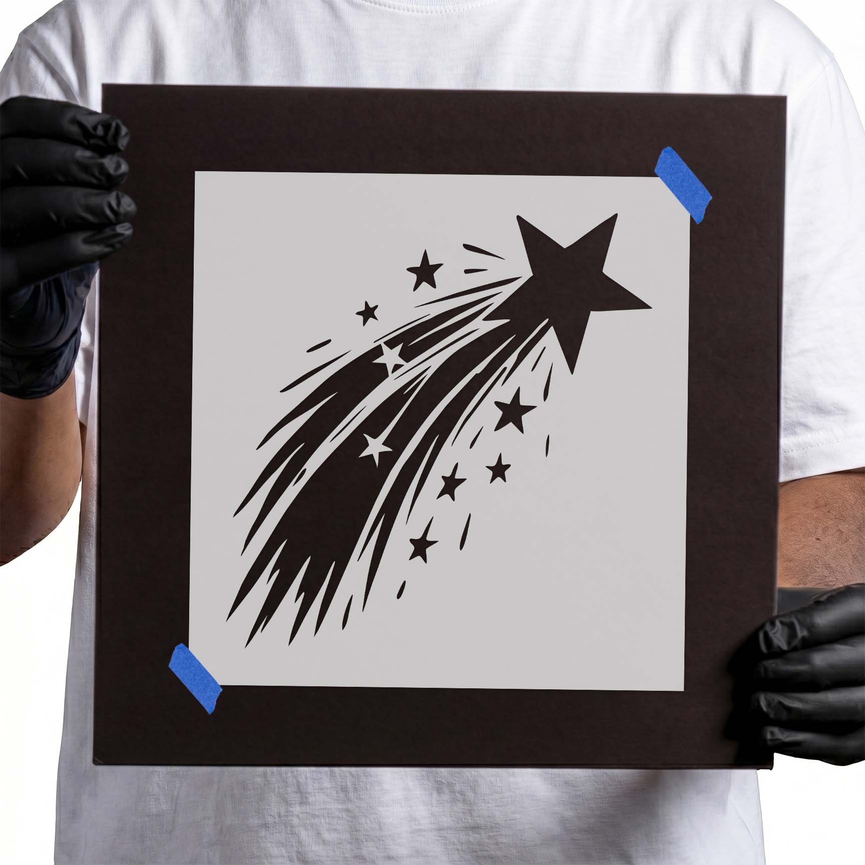 Person holding Shooting Star Trail Stencil taped to black cardboard