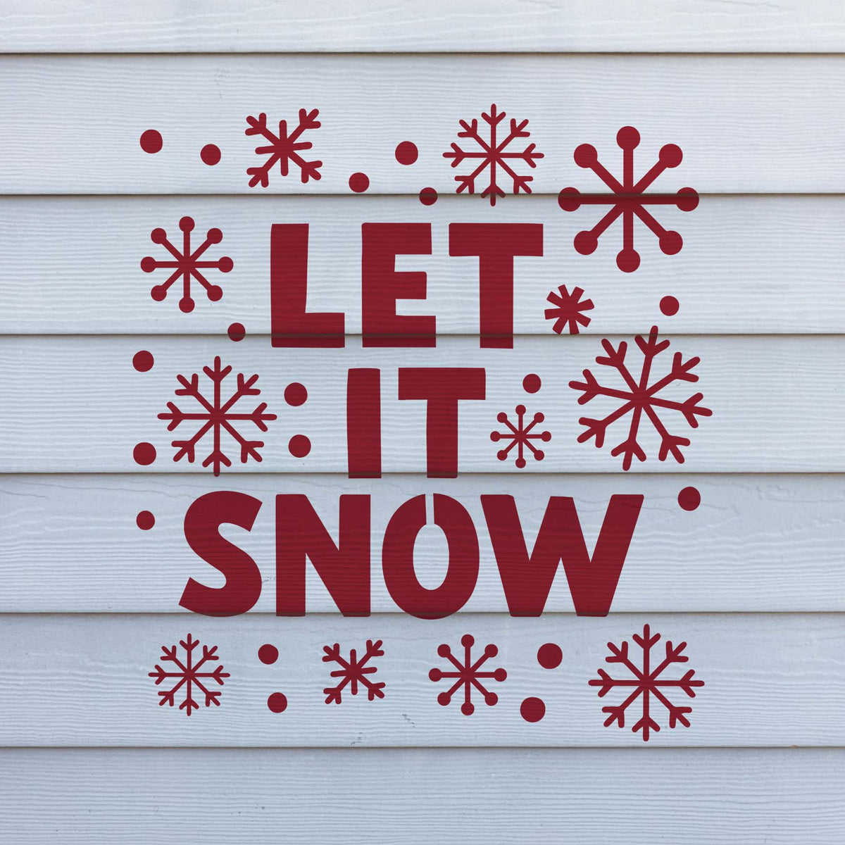 Red Snowflake Let It Snow Stencil decorates white siding with bold lettering and varied snowflakes.