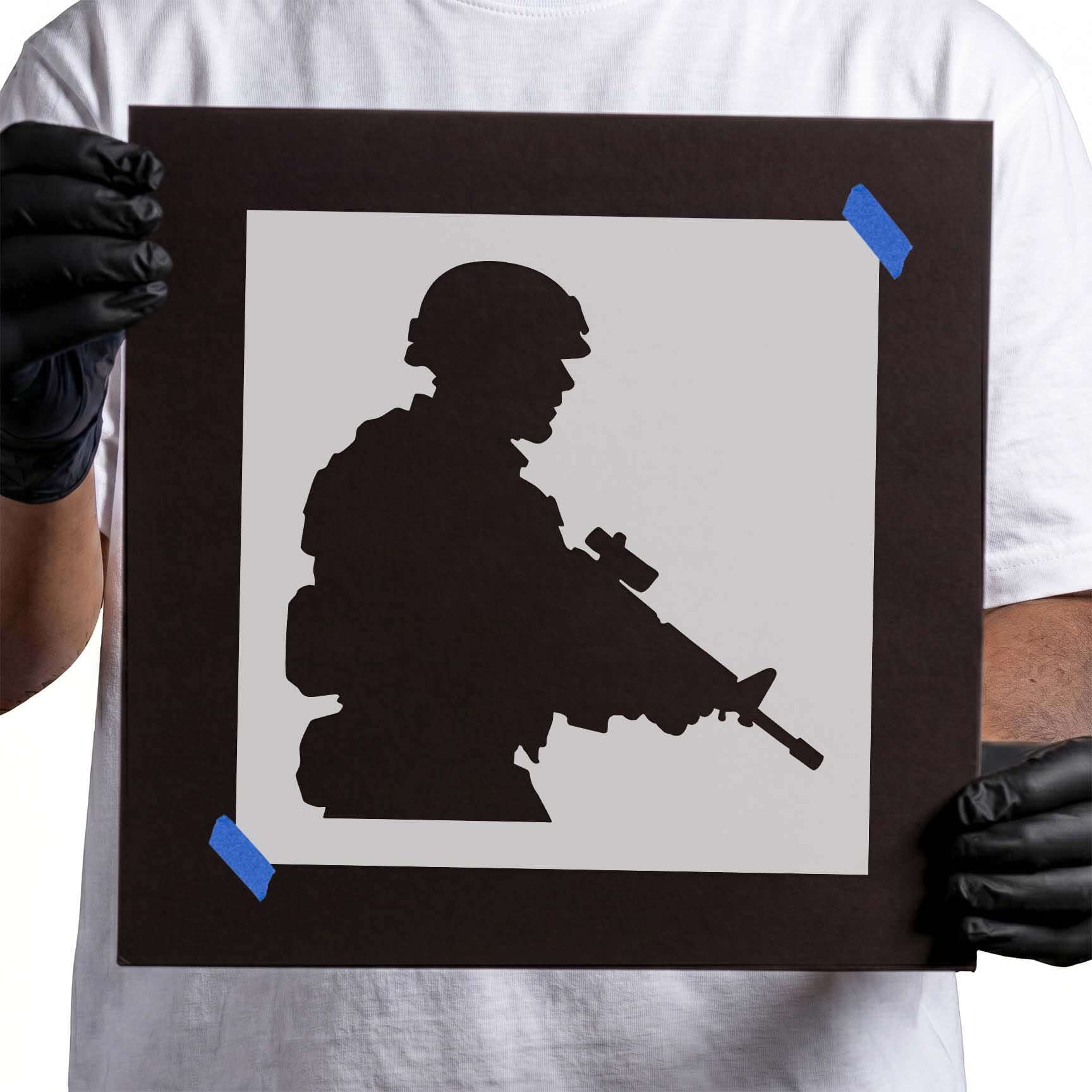 Person holding Tactical Soldier Silhouette Stencil taped to cardboard