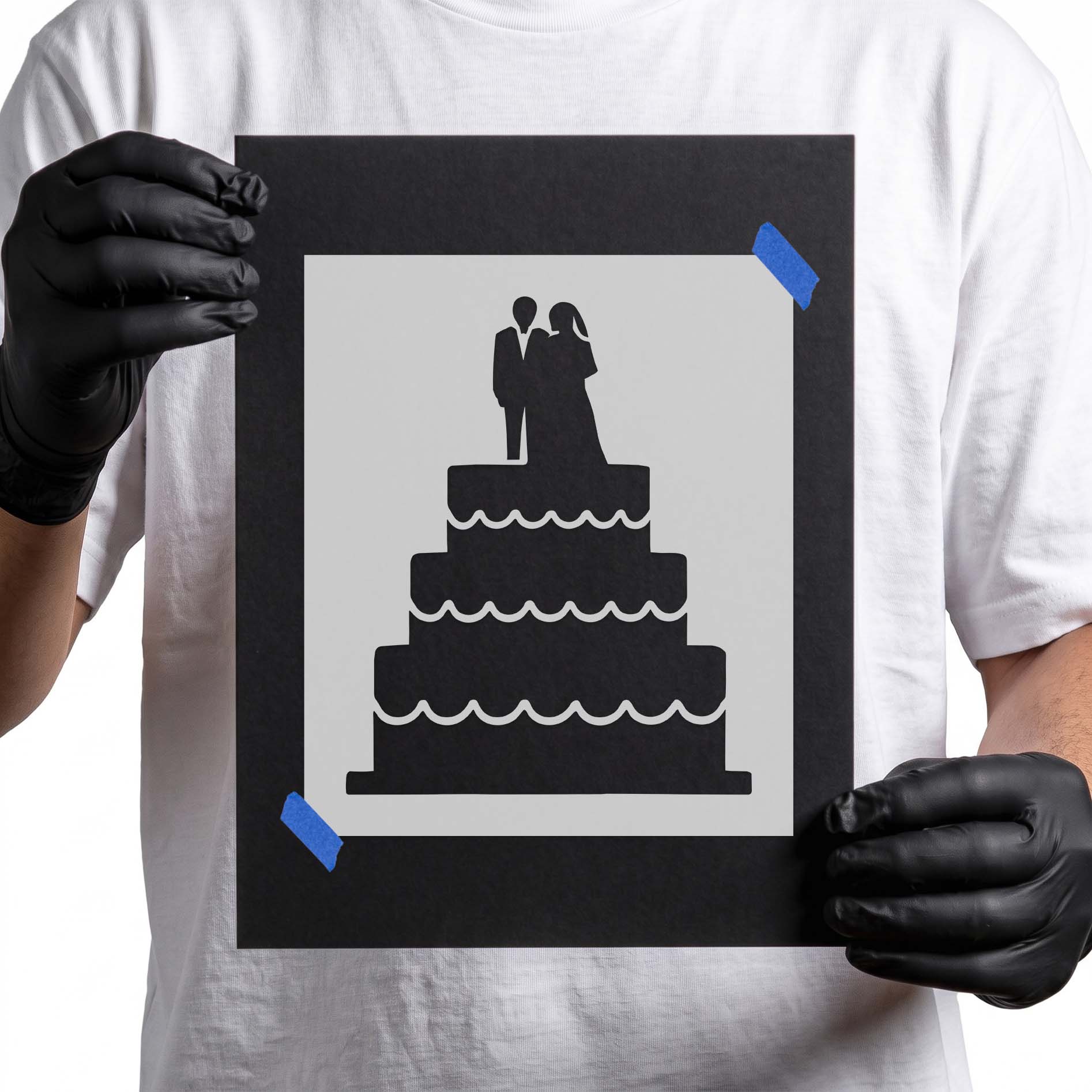 Gloved hands holding Tiered Wedding Cake stencil taped to black cardboard