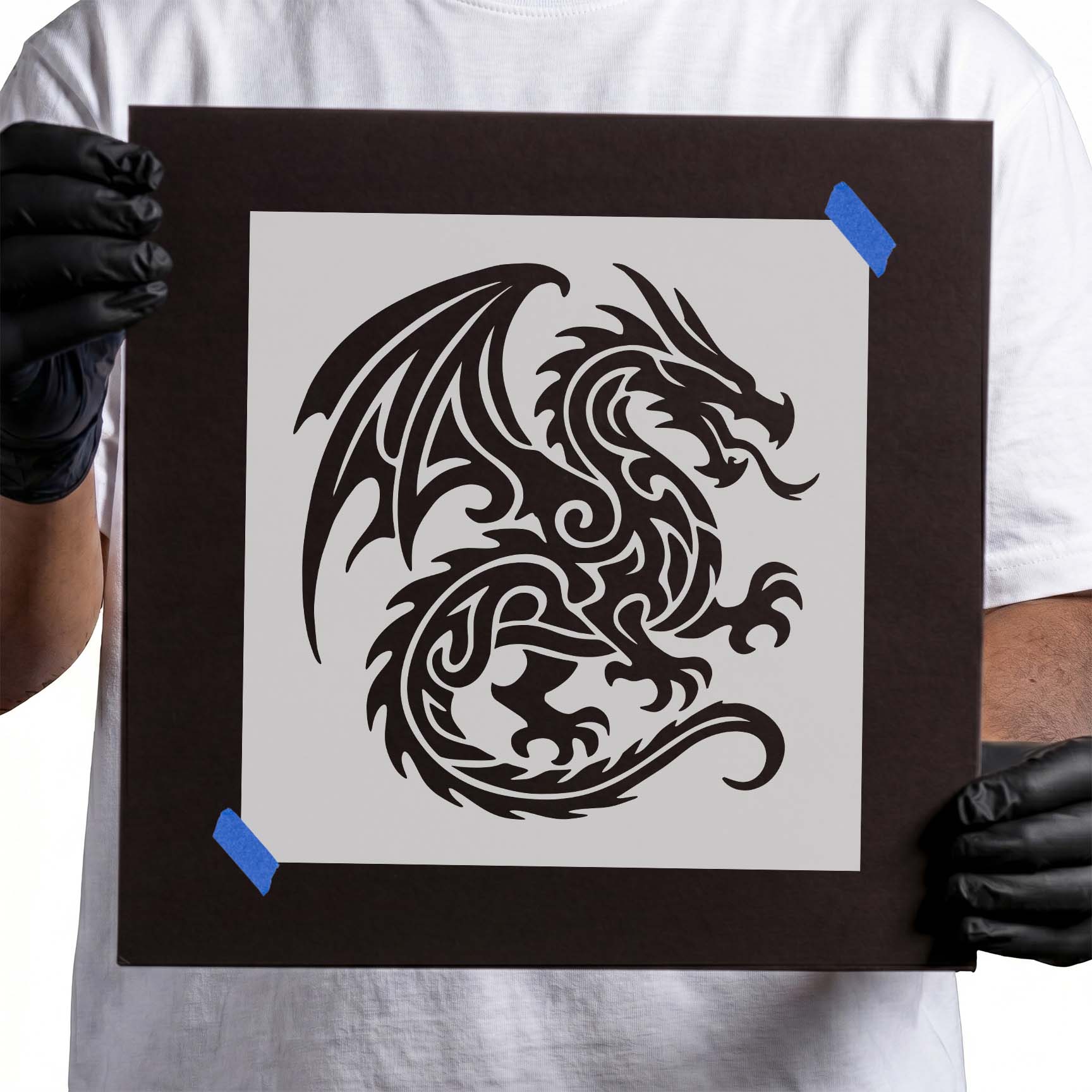 Person holding Tribal Fire Dragon Stencil taped to cardboard