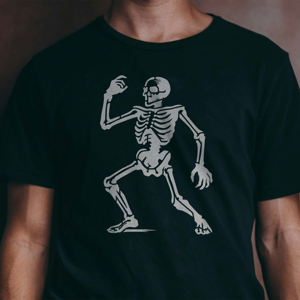 Animated Dancing Skeleton Stencil strikes a lively pose in silver across a black shirt