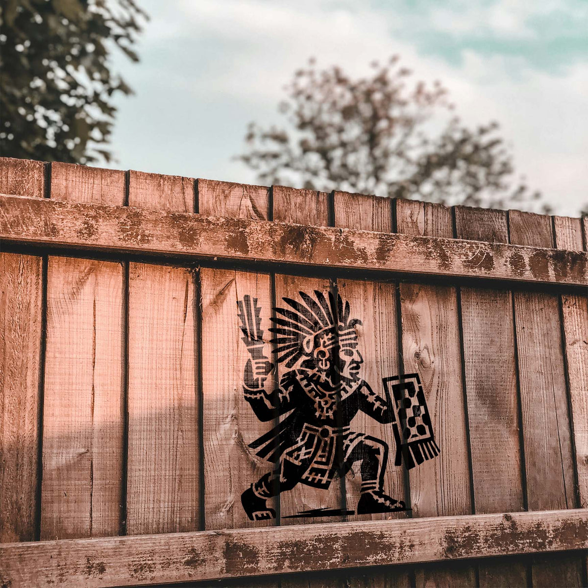 Aztec Warrior Shield Stencil painted black on a rustic wooden fence.