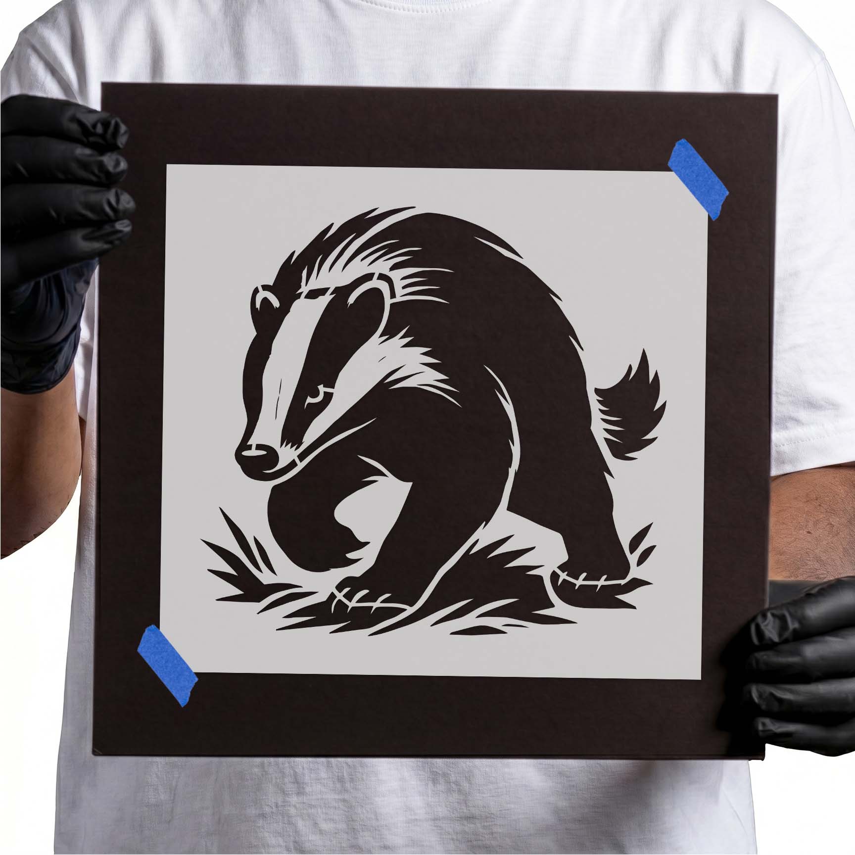 Person holding Walking Badger Stencil taped to cardboard