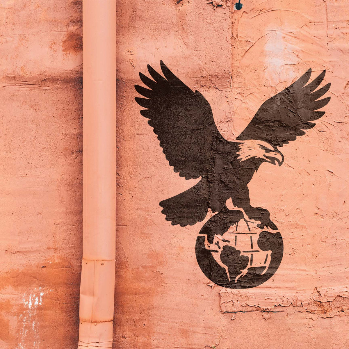 Bold Bald Eagle on Globe Stencil spreads its wings across a textured salmon-colored wall.