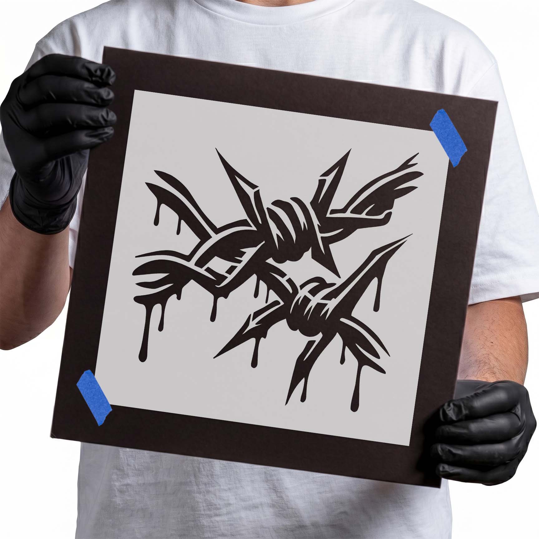 Person holding Dripping Barbed Wire Graffiti Stencil taped to cardboard
