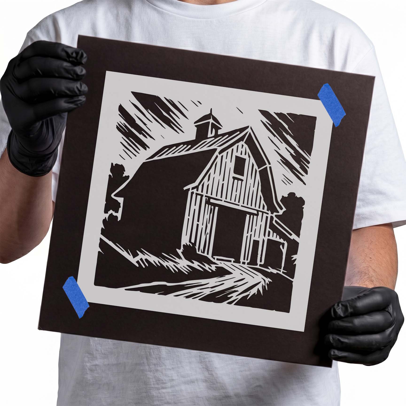 Person holding Rustic Gambrel Barn Stencil taped to cardboard