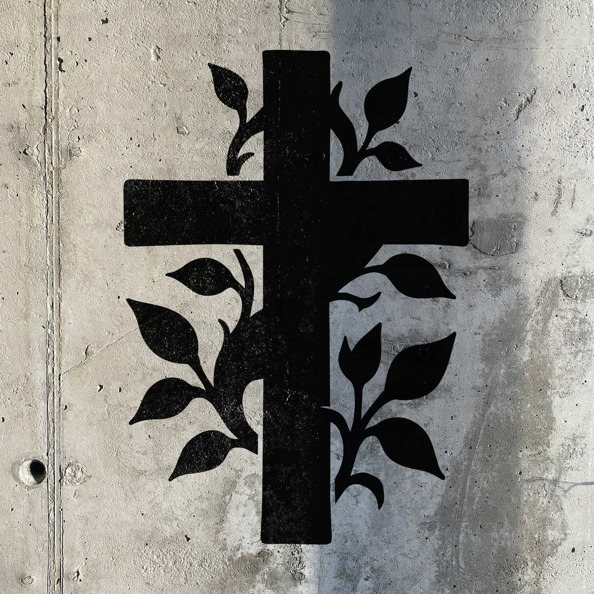 Botanical Vine Cross Stencil displayed in black on a textured concrete wall.
