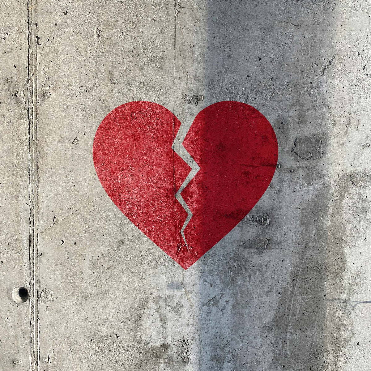 Painted on raw concrete, the Broken Heart Crack Stencil shows a vivid red heart split down the center