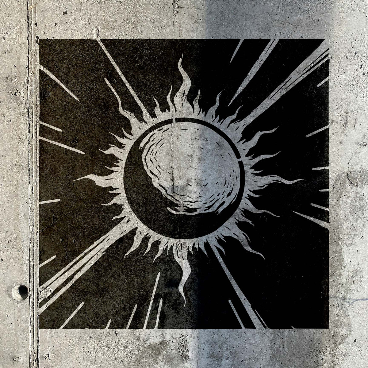Celestial Sunburst Eclipse Stencil reveals fiery solar rays in black on a textured concrete wall.