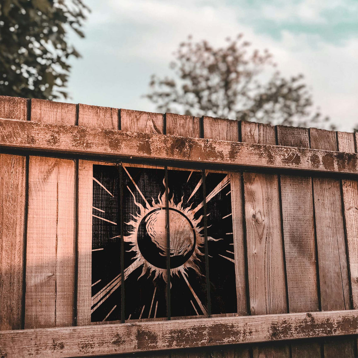 Against rustic wooden planks, the Celestial Sunburst Eclipse Stencil displays a dramatic solar eclipse.