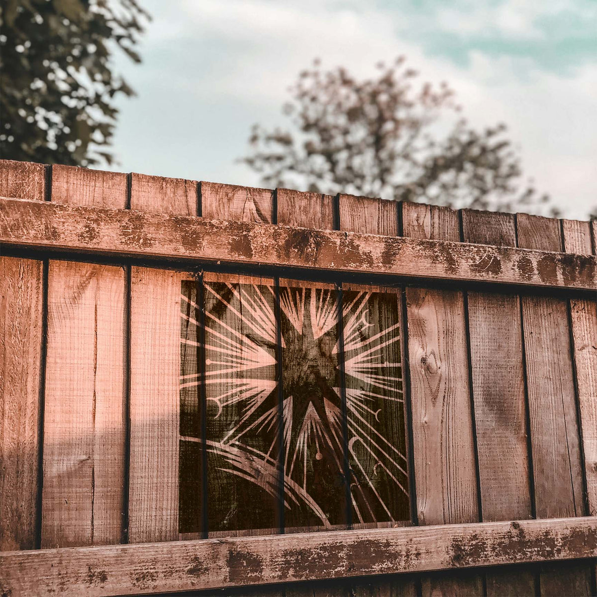 Celestial Sunburst Horizon Stencil painted across a rustic wooden fence with radiating rays