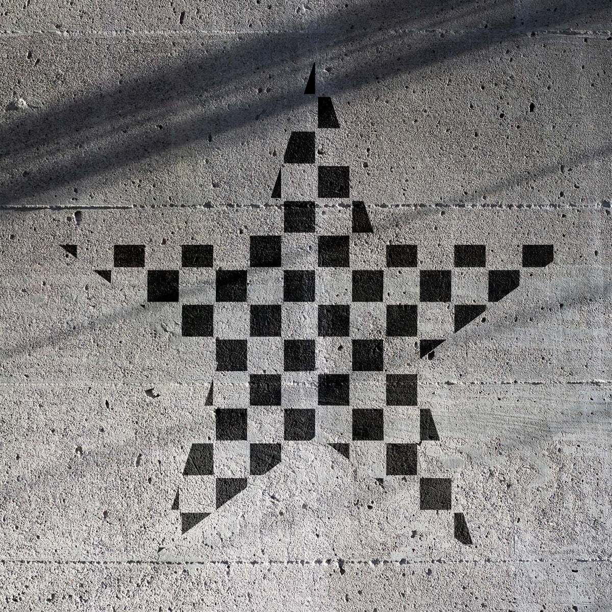 Checkerboard Star Stencil forms a bold black checkered star across a textured concrete wall